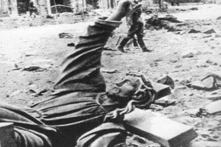 Zniszczona statua Chrystusa pośród gruzów; skutki wojny.