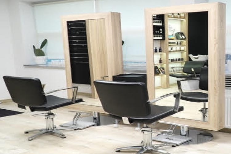 Nowoczesne wnętrze salonu fryzjerskiego ze stylowymi czarnymi fotelami i lustrzanymi schowkami.