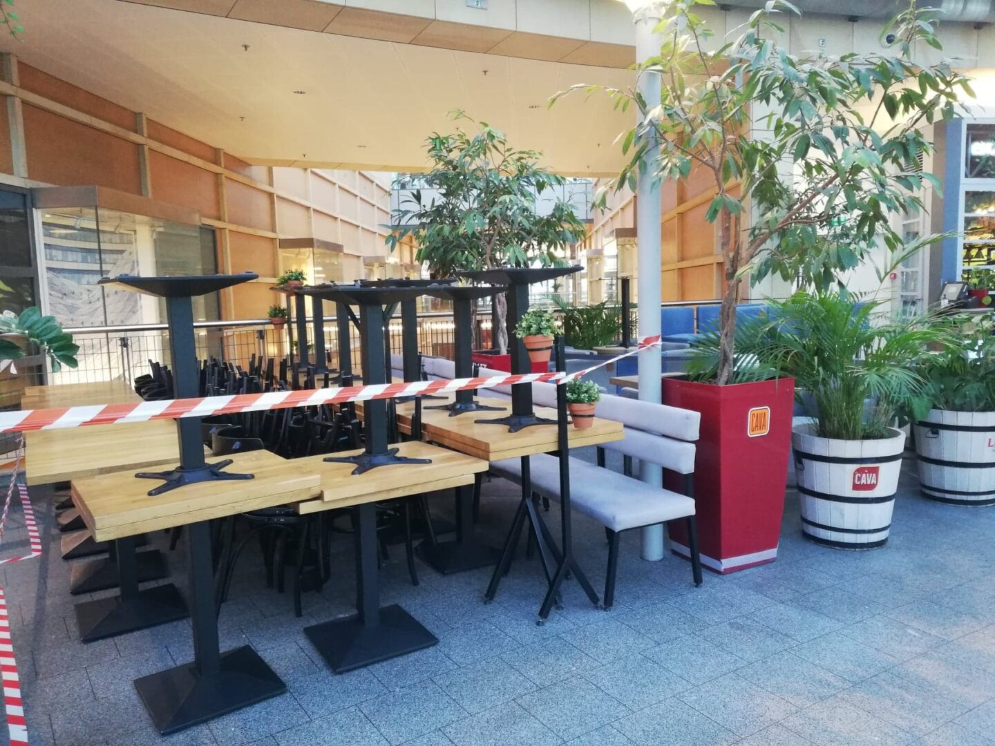 Puste stoliki i krzesła w restauracji odgrodzone linami w centrum handlowym.