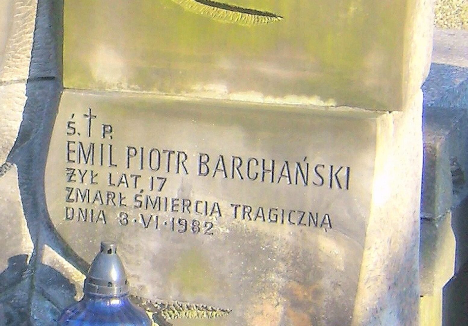 Close-up of a gravestone inscription: "† S. P. Emil Piotr Barchański, Żył lat 17, Zmarł śmiercią tragiczną dnia 8.VI.1982