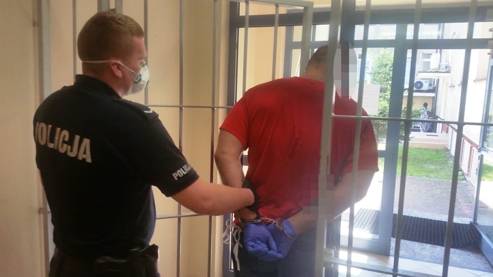 Policjant aresztujący podejrzanego w kajdankach. POLICJA.