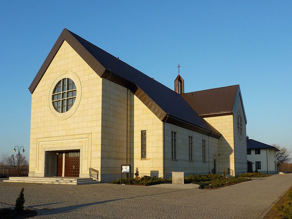 Nowoczesny beżowy kościół z ciemnym dachem i okrągłym oknem