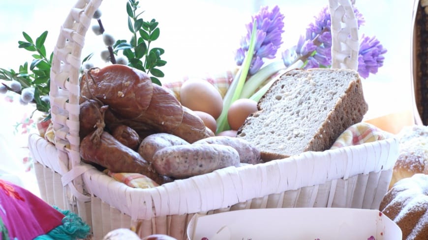Koszyk wielkanocny z mięsem, chlebem, jajkami i wiosennymi kwiatami. Proste tradycje wielkanocne.