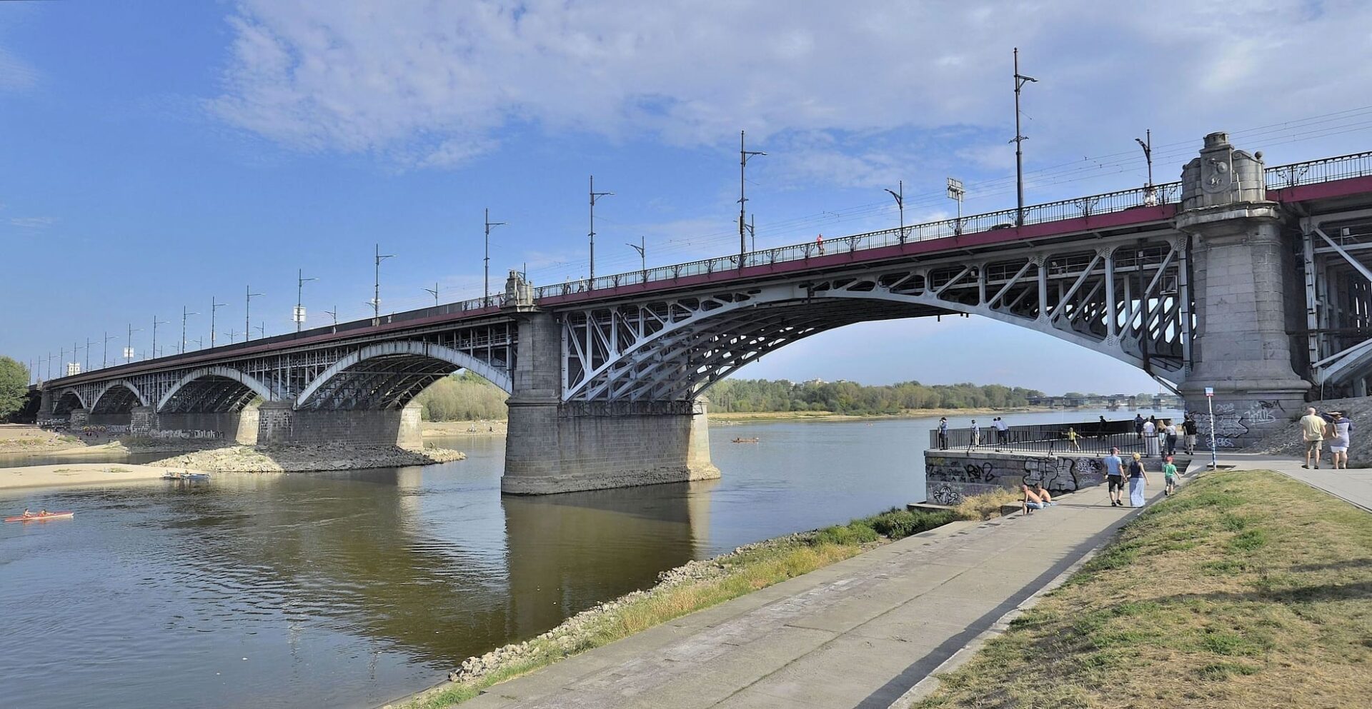 Most Poniatowskiego w Warszawie. Ludzie odpoczywają nad rzeką.