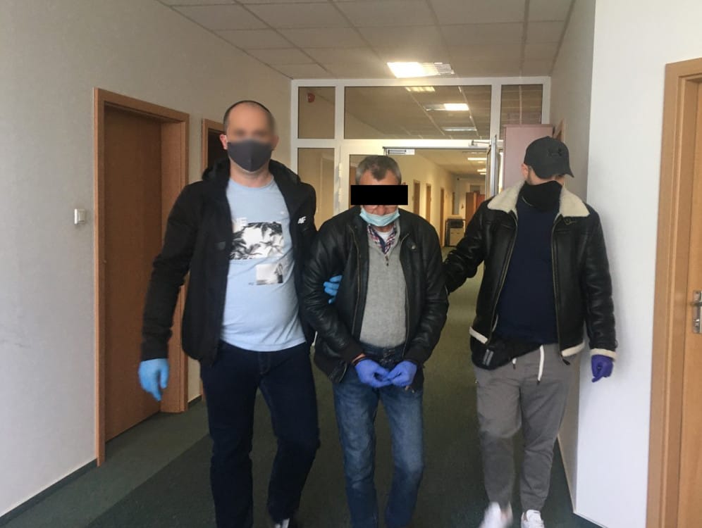 Trzech mężczyzn w areszcie, eskortowanych przez funkcjonariuszy organów ścigania.