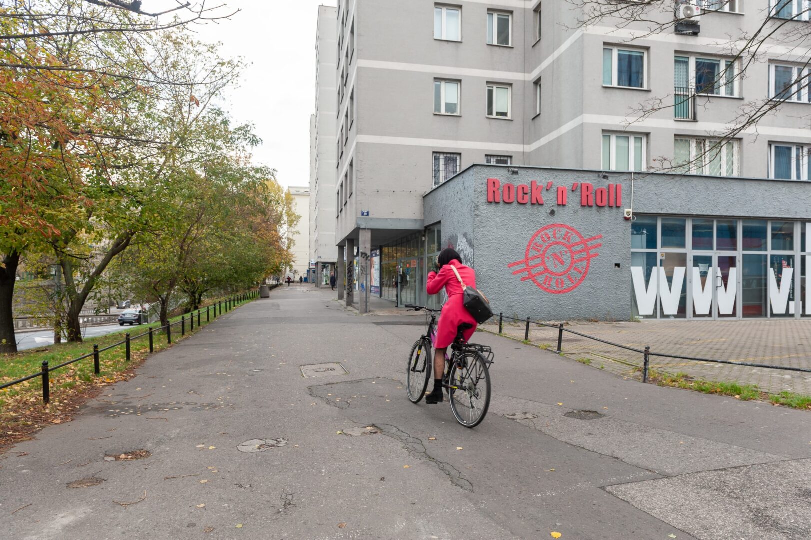 Kobieta jedzie na rowerze obok klubu „Rock 'n' Roll” przy Trasie Łazienkowskiej, w pobliżu przyszłego terenu zielonego.