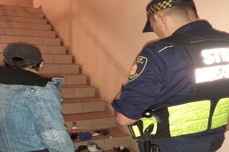 Policjant badający miejsce zdarzenia, w którym na schodach znajdowała się podejrzana osoba.