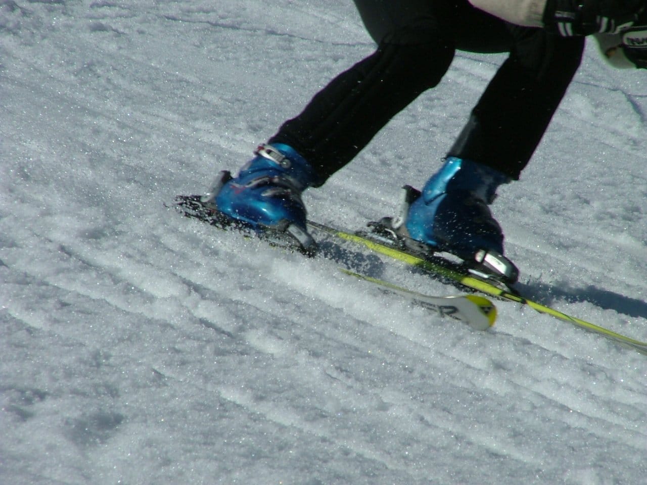 Skier's blue ski boots carving turns on snowy Mazowsze slope.