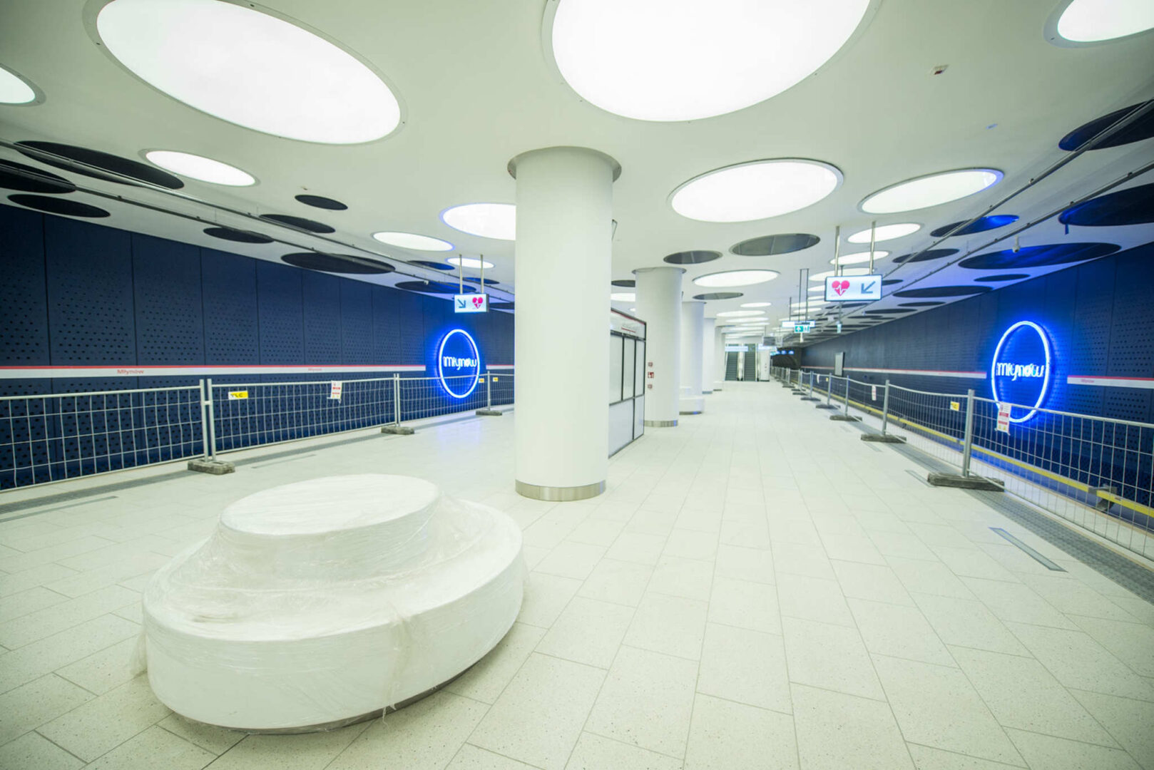 Empty Młynów metro station platform, awaiting opening. "Młynów" signage visible.