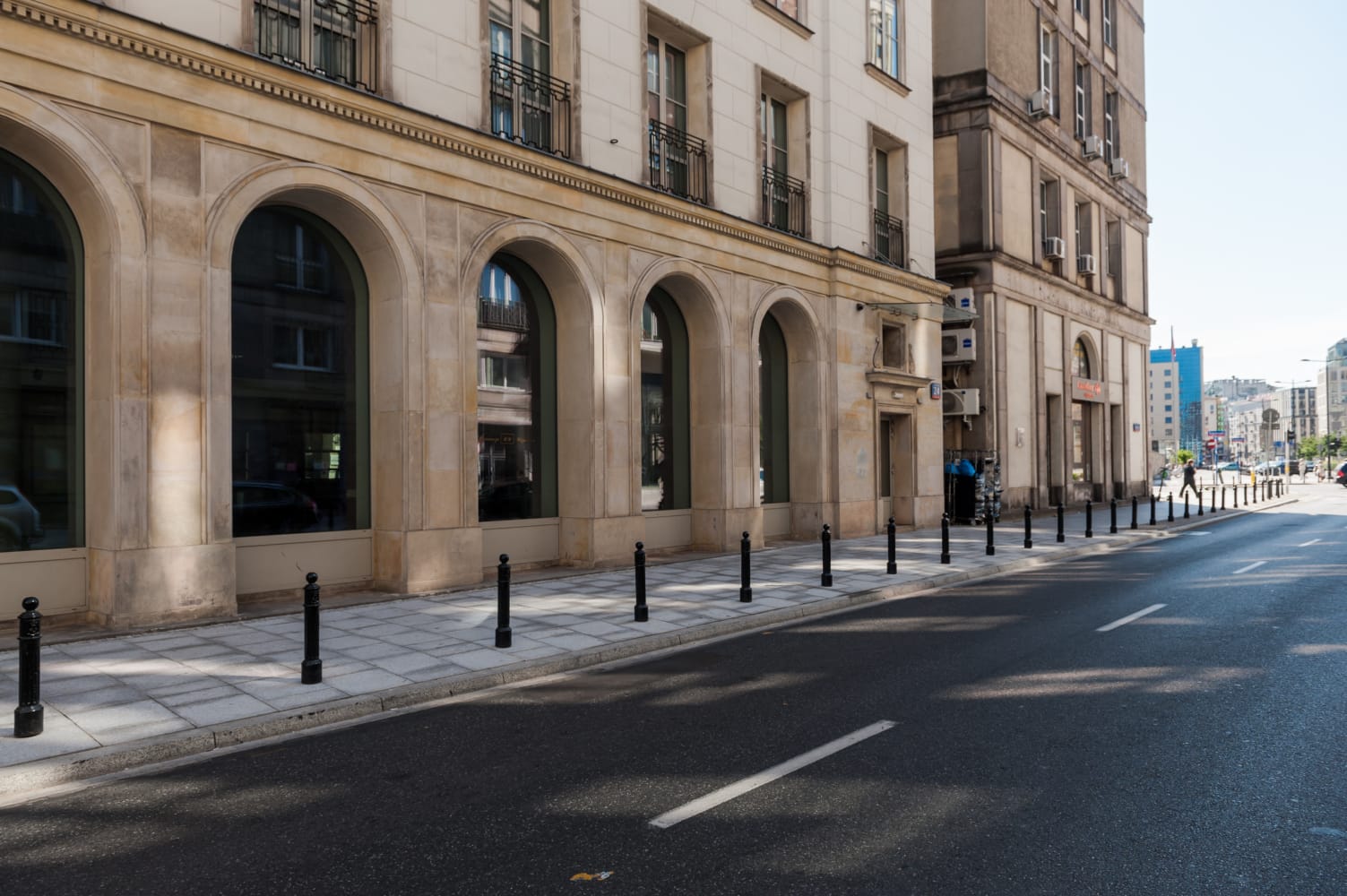 Elegancka warszawska ulica z klasyczną architekturą i łukowatymi oknami.
