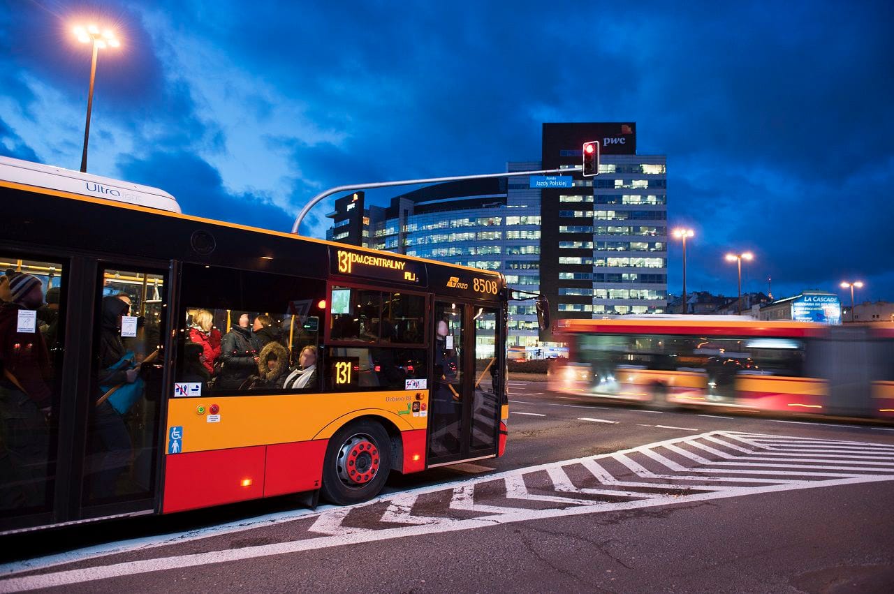 Nocna scena autobusu miejskiego na przejściu dla pieszych, z nowoczesnym budynkiem biurowym w tle. Numer autobusu 8508, linia 131.
