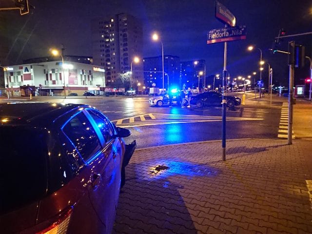 Nocny wypadek w Gocławiu; radiowóz z migającymi światłami, uszkodzone pojazdy.