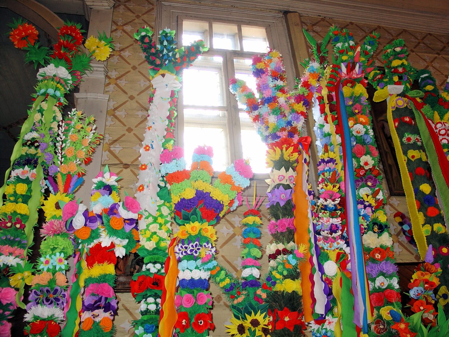 Kolorowe, ręcznie robione palmy wielkanocne wystawione w kościele. Ponura Wielkanoc.