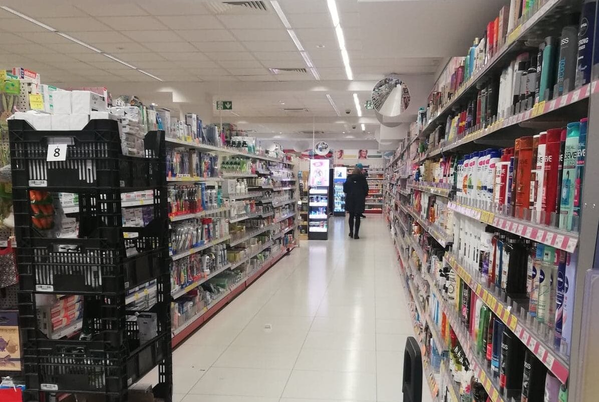 Alejka w drogerii lub aptece, na której znajdują się półki z produktami do pielęgnacji ciała.