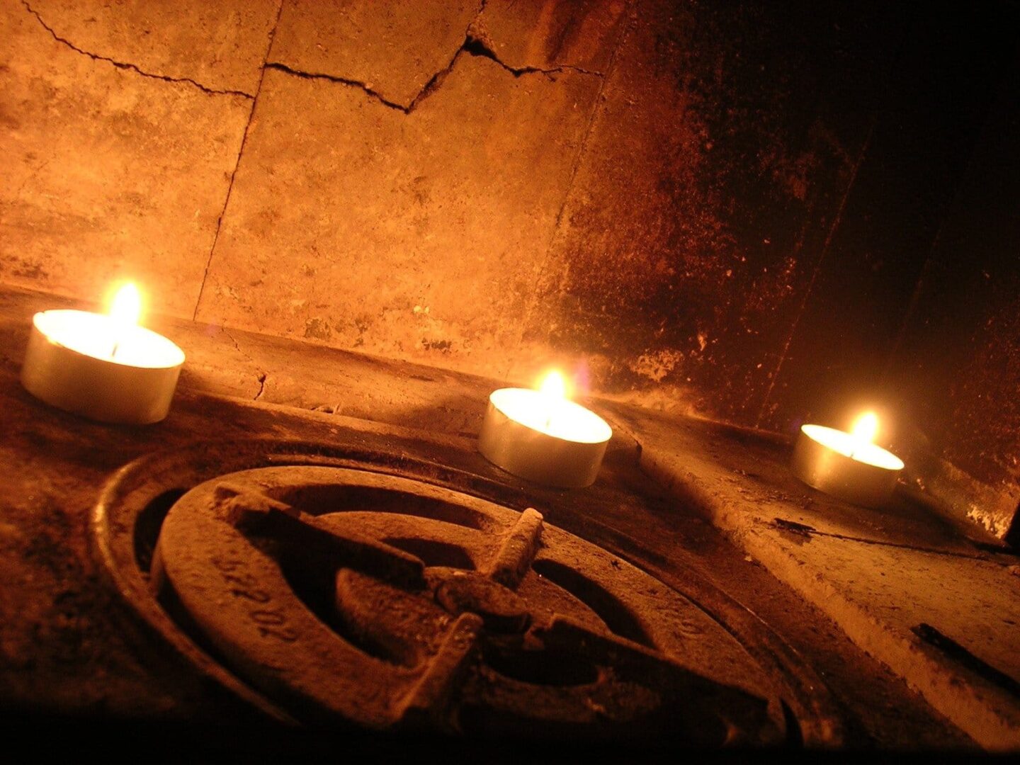 Trzy świece palące się w rustykalnym kominku