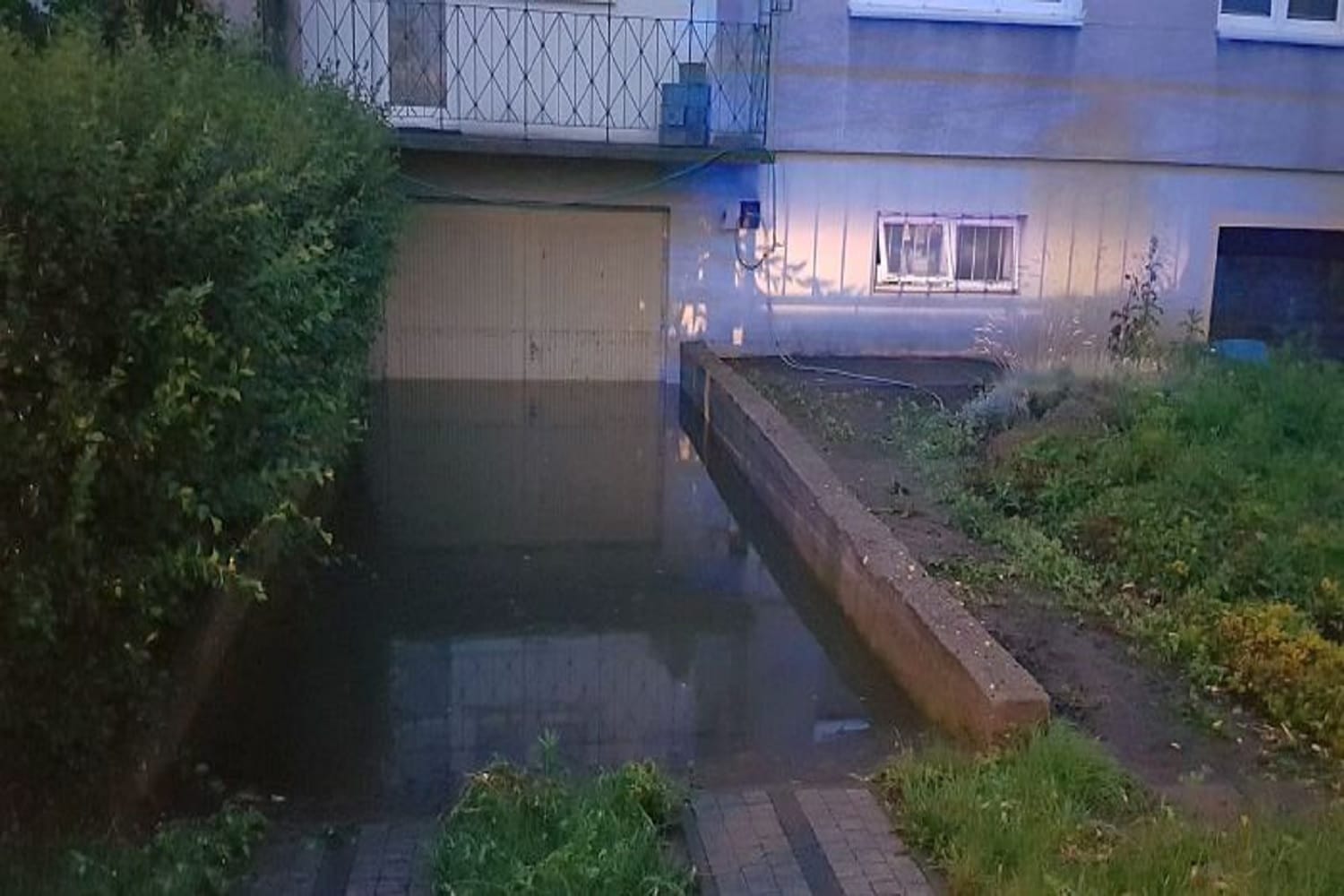 Zalany podjazd i garaż; szkody spowodowane wodą na skutek intensywnych opadów deszczu.