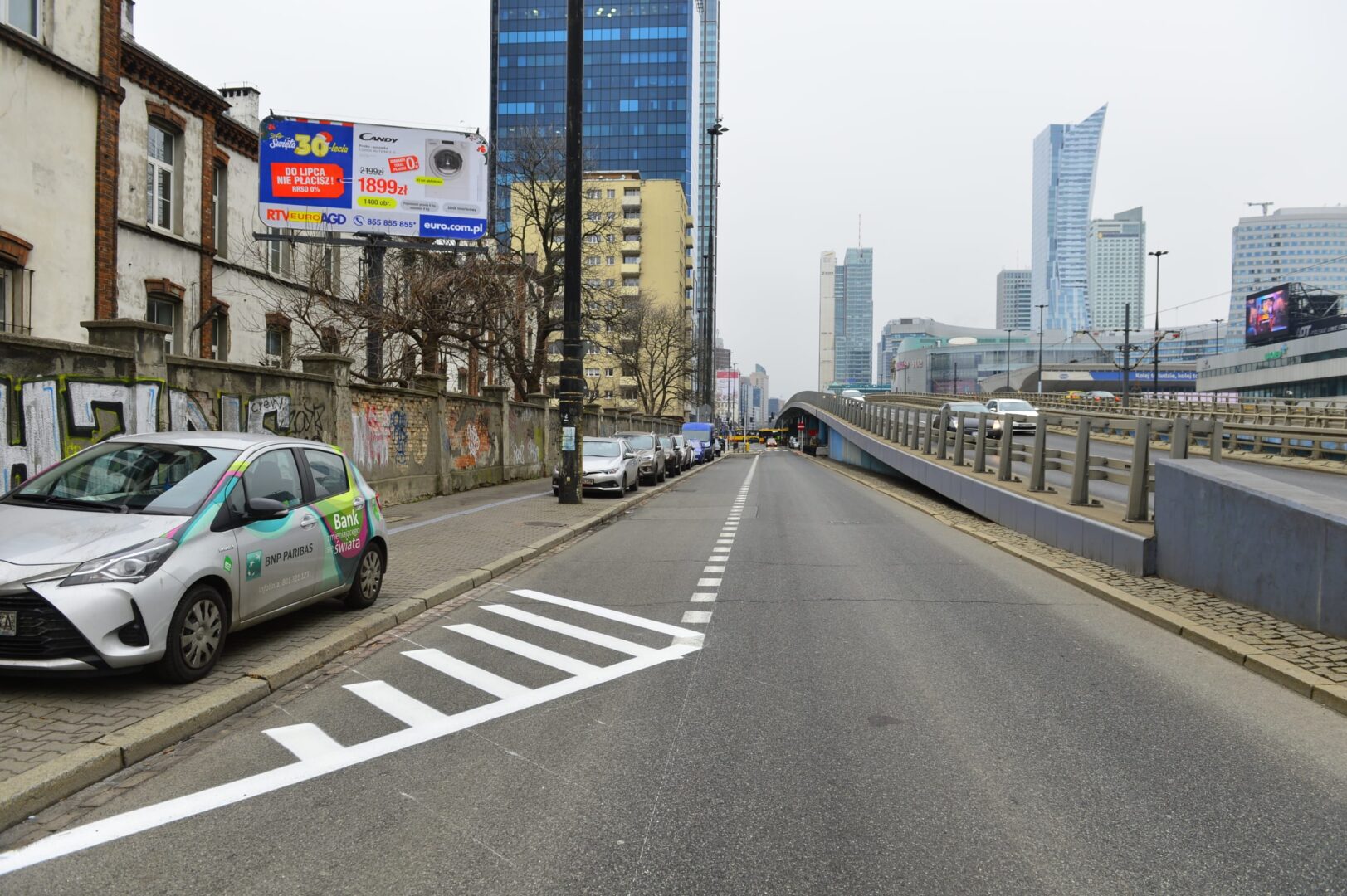 Scena uliczna Warszawy z nowoczesnymi wieżowcami i zaparkowanym samochodem