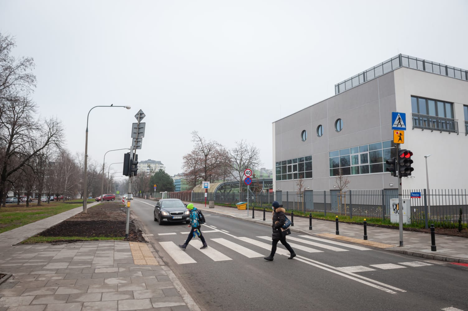 Piesi przechodzący przez ulicę na przejściu dla pieszych w pobliżu nowoczesnego budynku.