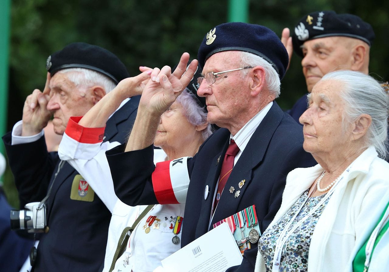 Weterani II wojny światowej salutują podczas ceremonii. Widoczne polskie odznaczenia wojskowe.
