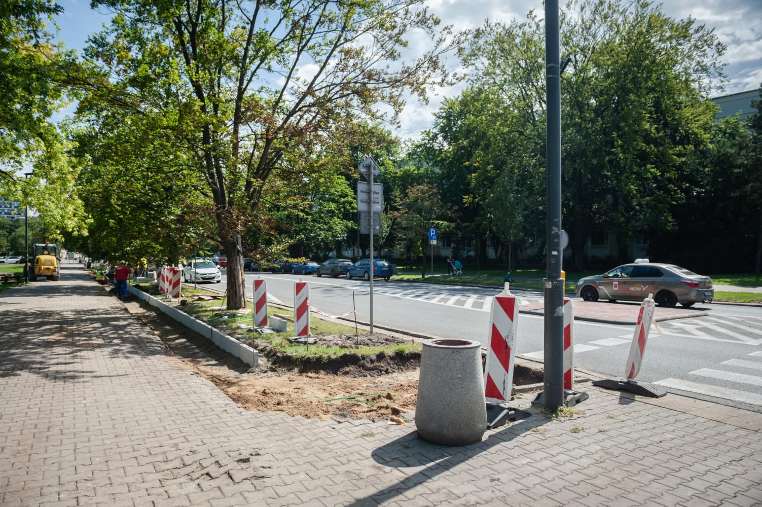 Miejski krajobraz uliczny objęty budową chodników, układaniem nowej kostki brukowej i sadzeniem drzew.