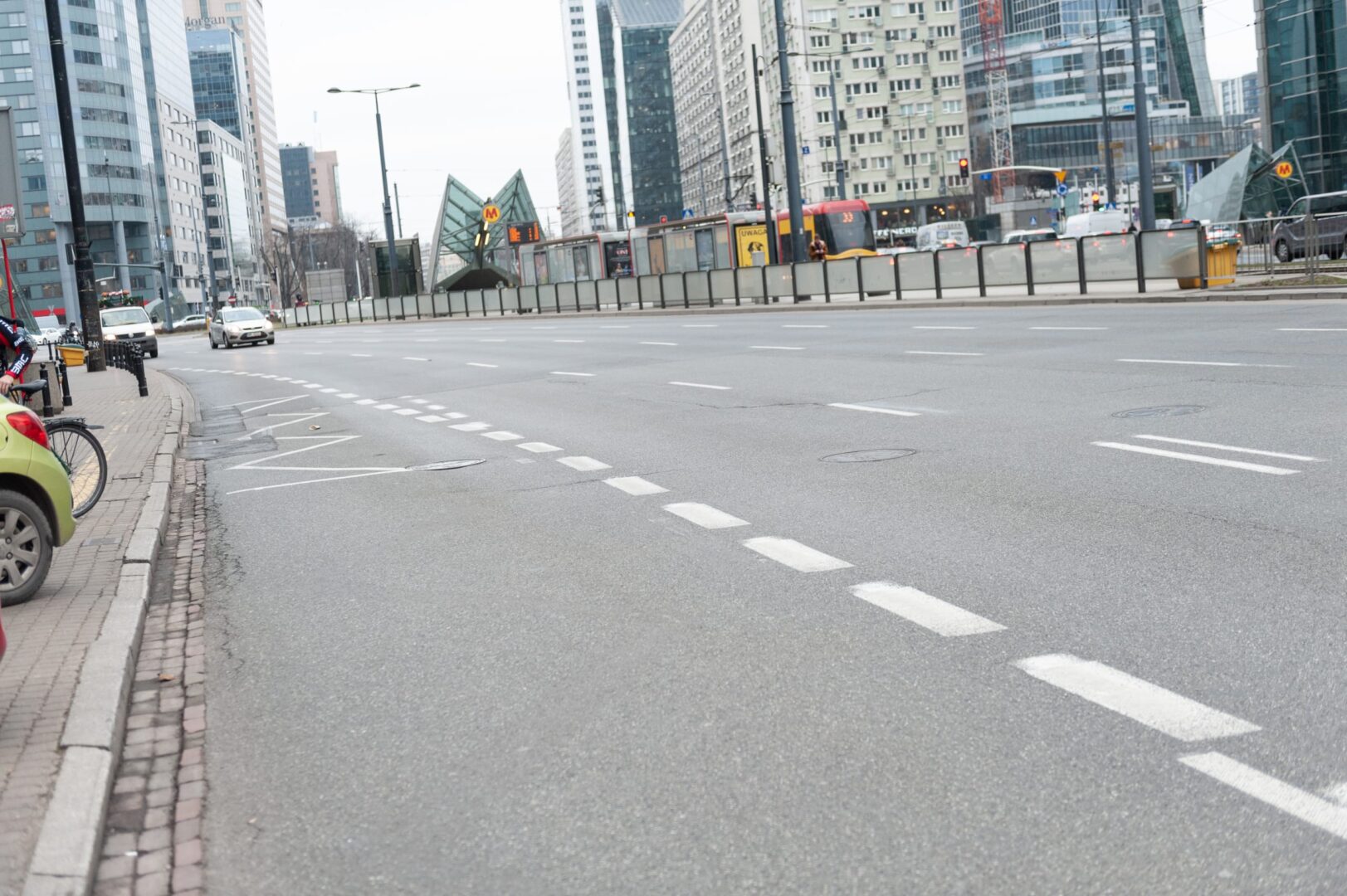 Pusta ulica miejska z nowoczesnymi budynkami i przystankiem tramwajowym.