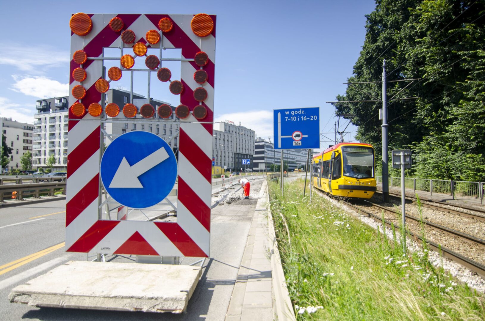 Budowa drogi ze światłami ostrzegawczymi, znakiem objazdu i tramwajem.