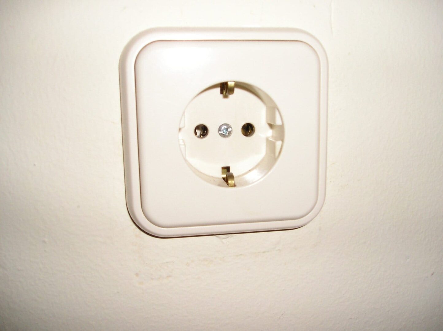 Zbliżenie standardowego europejskiego gniazdka elektrycznego w ścianie.
