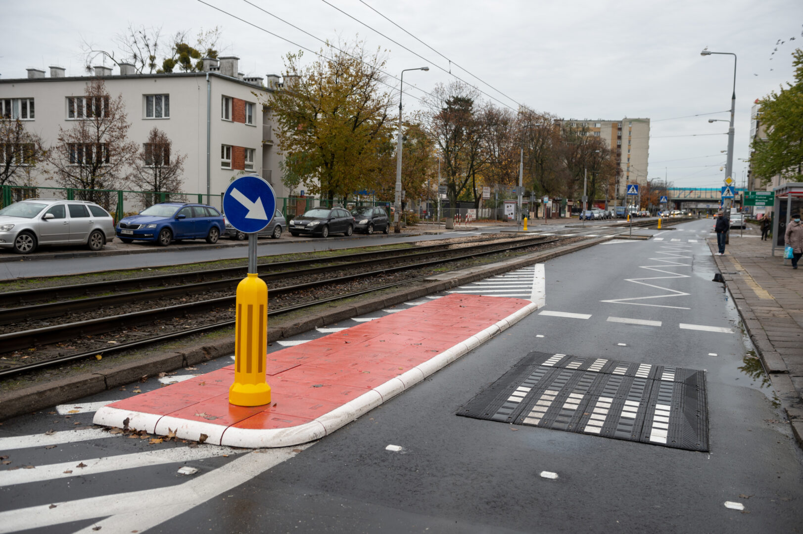 Tory tramwajowe i przejście dla pieszych z progiem zwalniającym, przedstawiające scenę ulicy miejskiej.