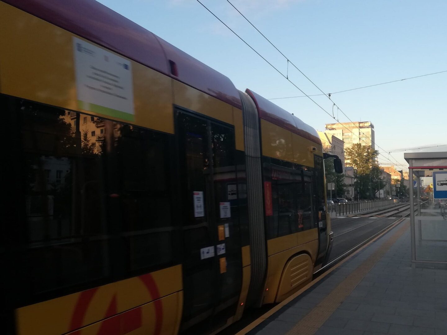 Nowoczesny żółty i bordowy tramwaj zbliżający się do stacji