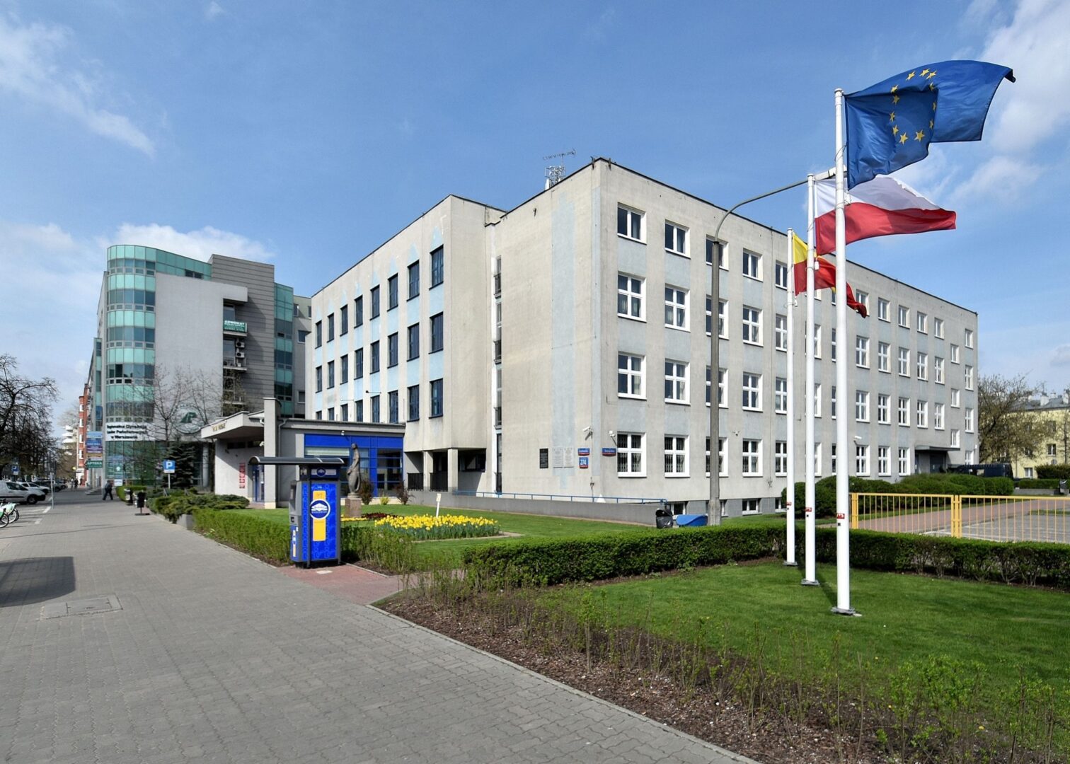 Nowoczesny budynek biurowy z flagami Polski i UE.