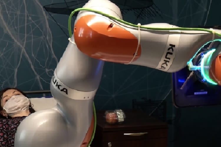 Robotyczne ramię Kuka pomaga pacjentowi na szpitalnym łóżku.