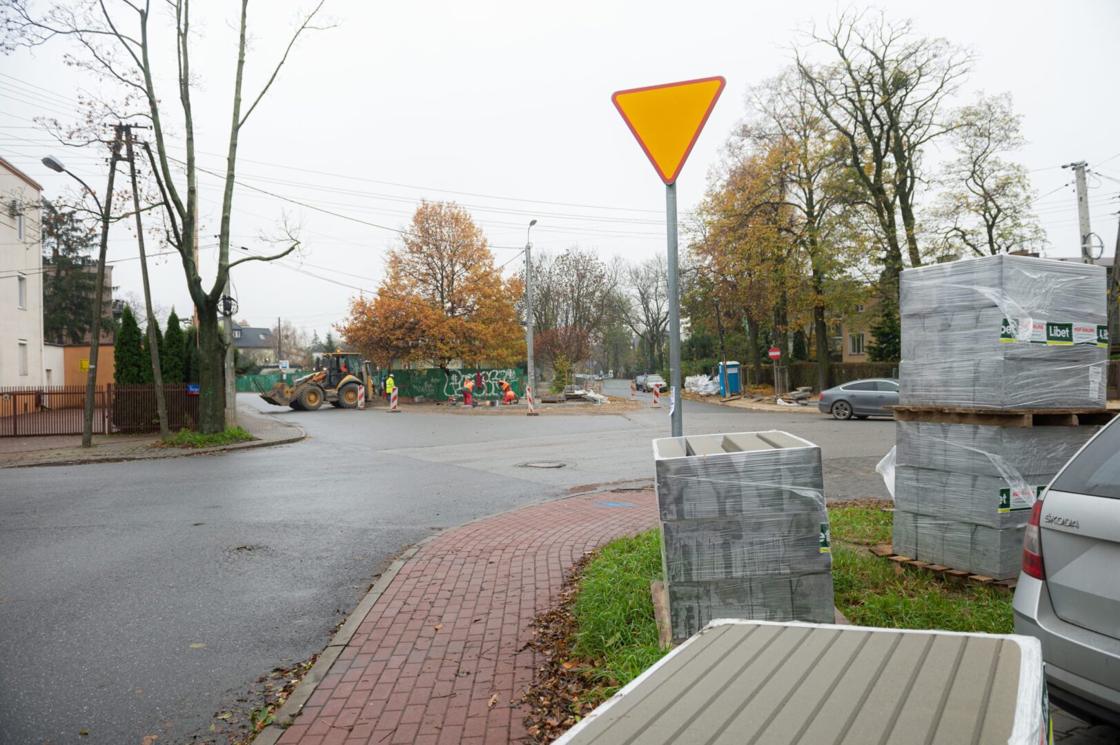Robotnicy drogowi w pobliżu żółtego znaku ustąp pierwszeństwa i materiałów budowlanych