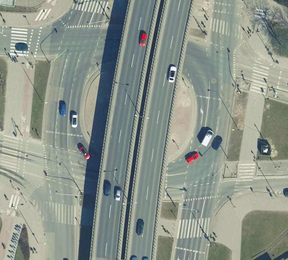 Widok z lotu ptaka na węzeł drogowy z wieloma samochodami i przejściami dla pieszych.