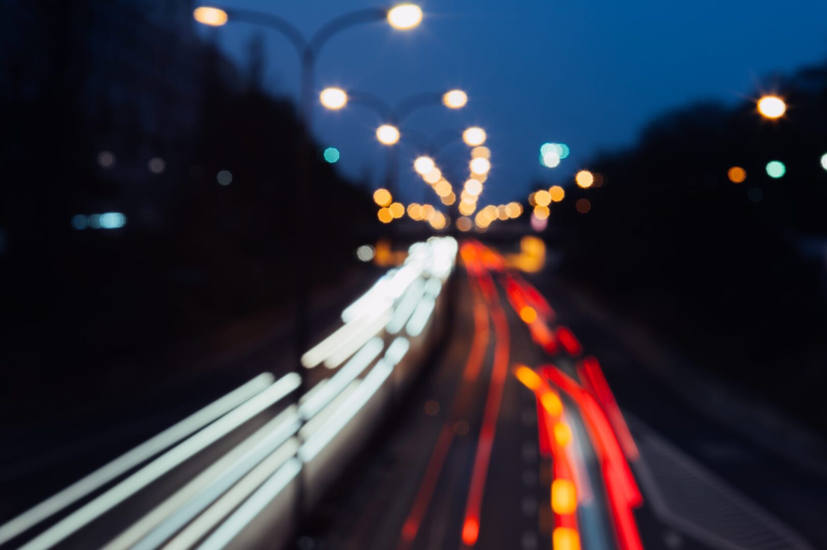 Zamazany obraz nocnego ruchu w Warszawie, pokazujący zmniejszony ruch pojazdów.