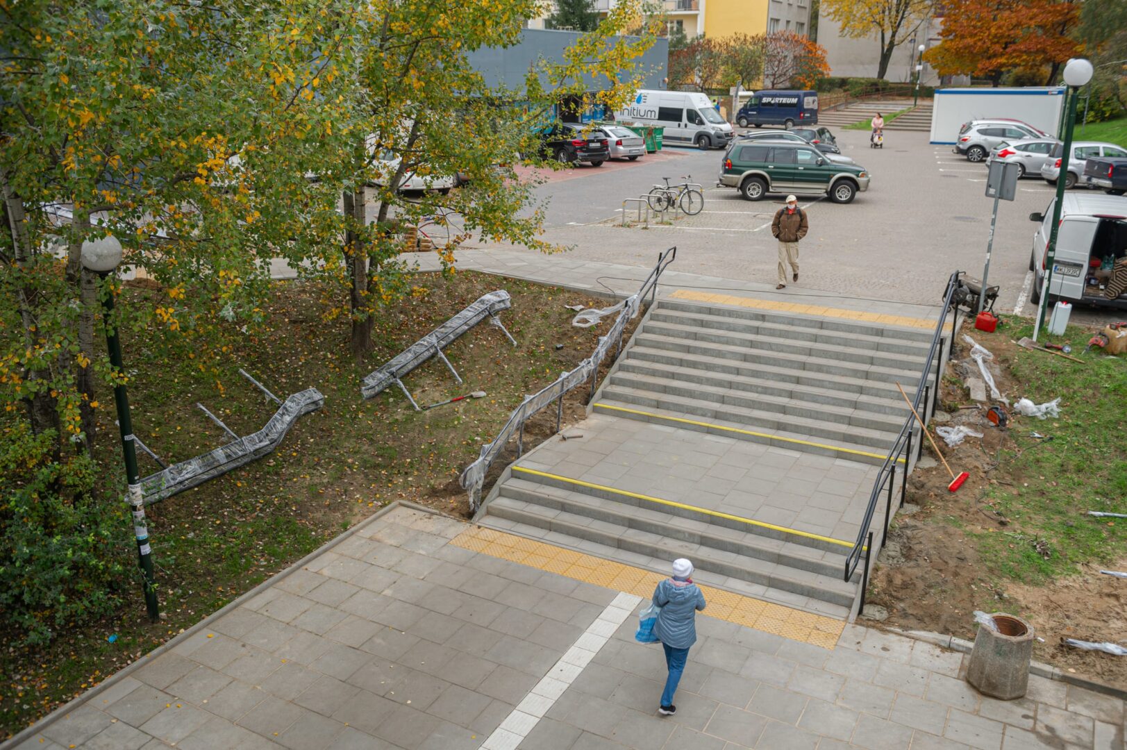 Robotnicy budowlani montują nowe schody i balustrady w pobliżu parkingu.