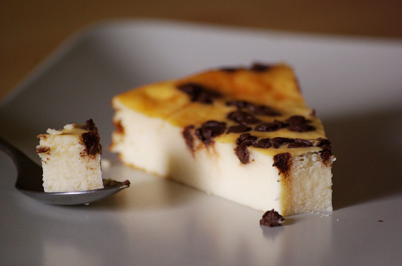Kawałek kremowego sernika z kawałkami czekolady na talerzu