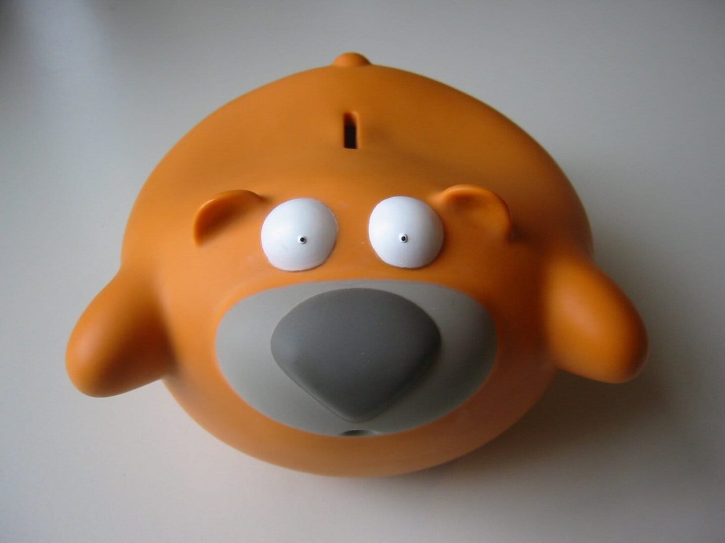 Pomarańczowa skarbonka w kształcie misia z dużymi oczami