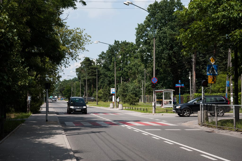 Przejście dla pieszych i samochody na ulicy mieszkalnej w Wawrze, Polska. Planowane są nowe sygnalizacje świetlne na tym skrzyżowaniu.
