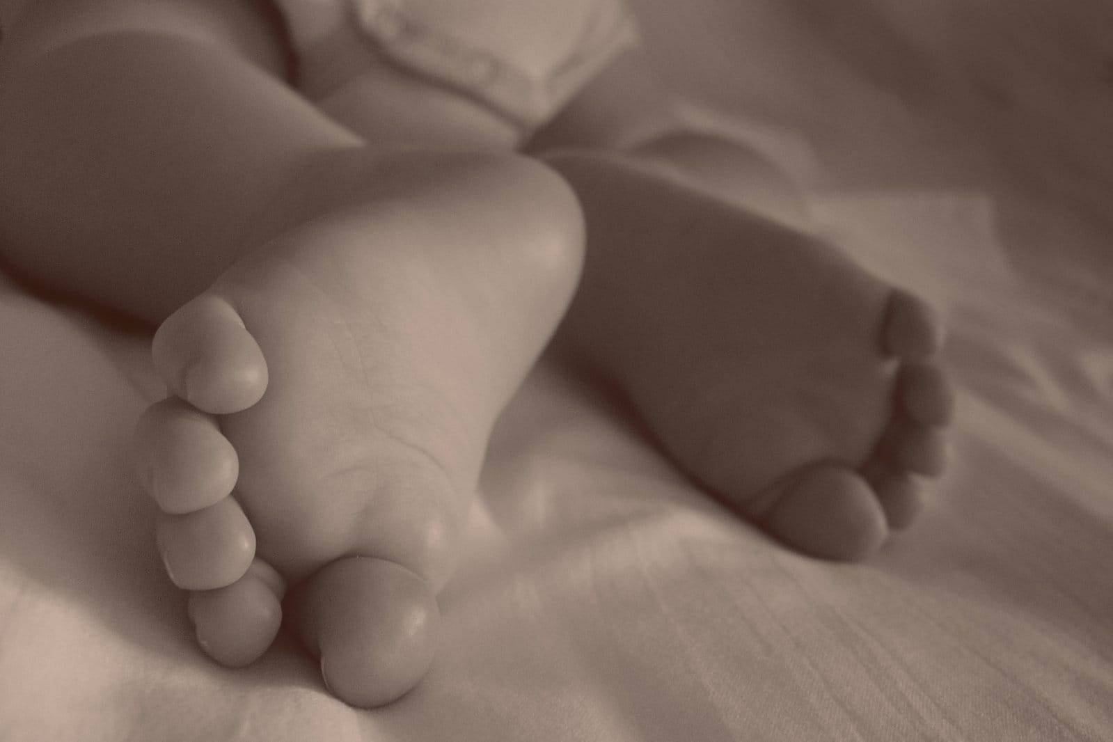 Zbliżenie stóp dziecka leżących na miękkim, białym kocyku.