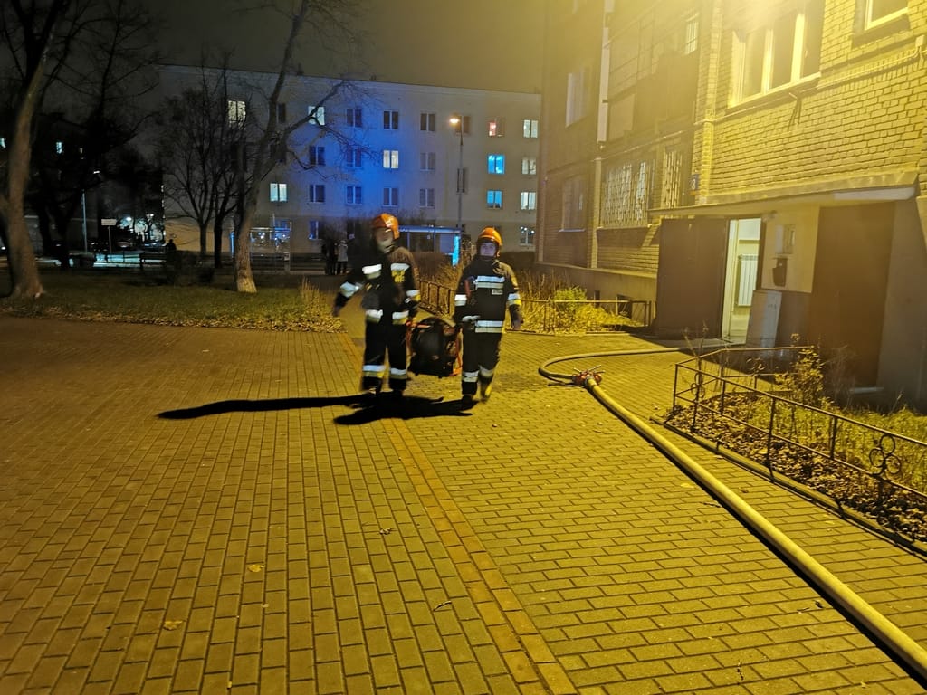 Dwóch strażaków niesie nosze po nocnym wypadku.