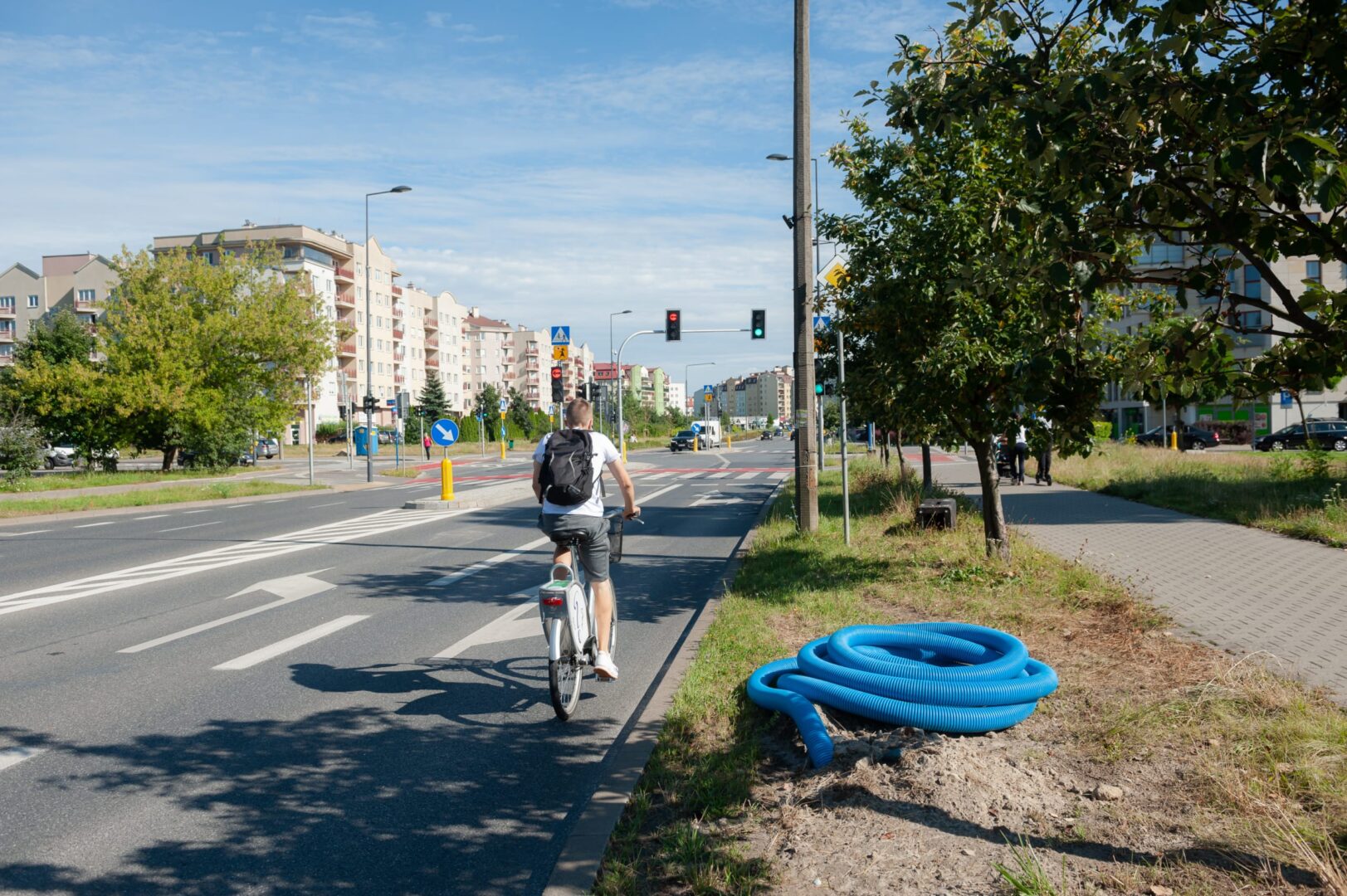 Mężczyzna jedzie na rowerze po miejskiej ścieżce rowerowej, przejeżdżając obok sygnalizacji świetlnej.