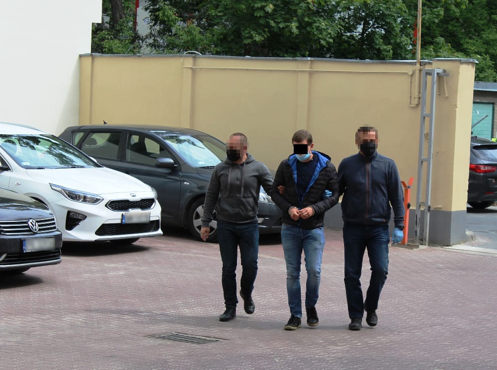 Trzech mężczyzn w kajdankach eskortowanych przez policjantów