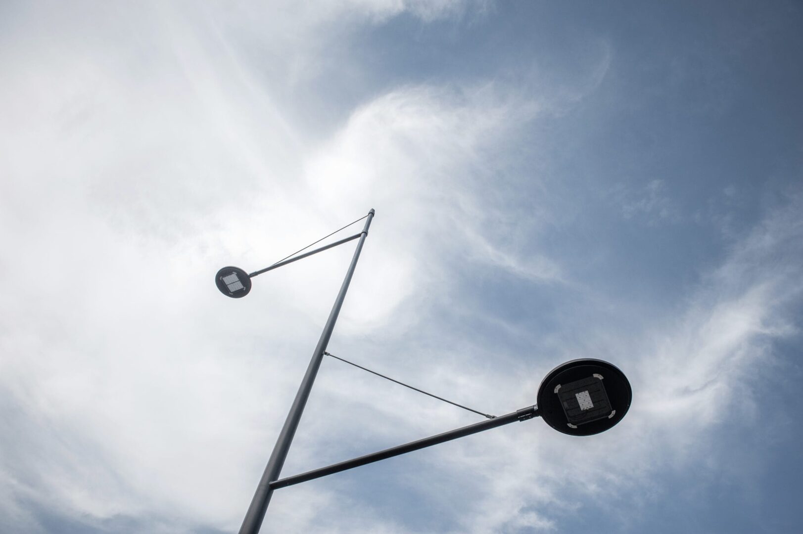 Nowoczesna latarnia uliczna z dwoma diodami LED na tle zachmurzonego nieba.