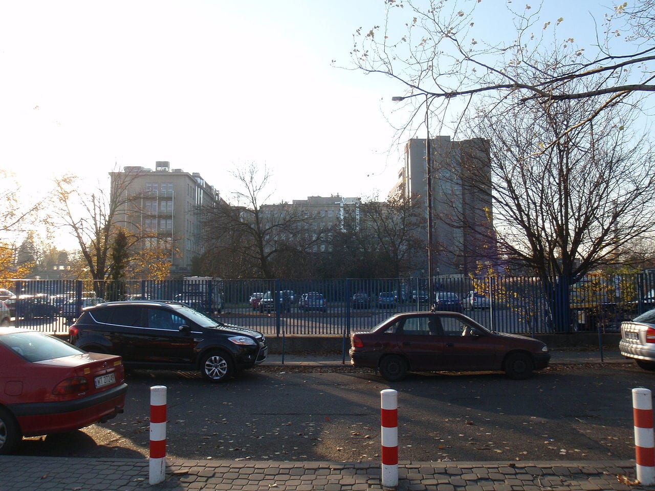 Samochody zaparkowane w pobliżu budynku szpitala w słoneczny dzień.