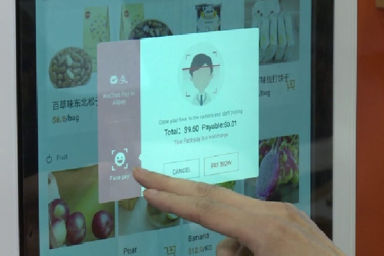 Klient korzystający z rozpoznawania twarzy, aby zapłacić w samoobsługowym kiosku kasowym. Łącznie: 9,60 USD