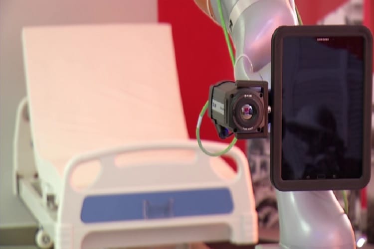 Ramię robota z kamerą i wyświetlaczem tabletu przy łóżku szpitalnym