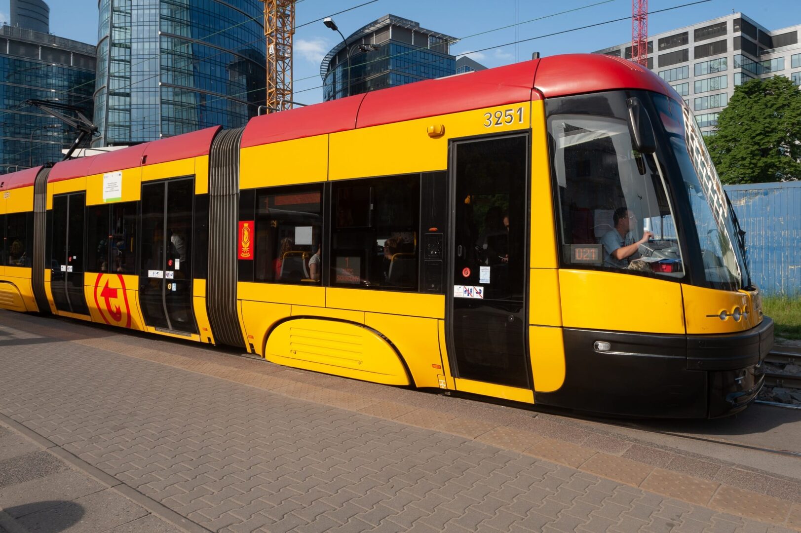 Nowoczesny tramwaj żółto-czerwony, numer 3251, w otoczeniu miejskim