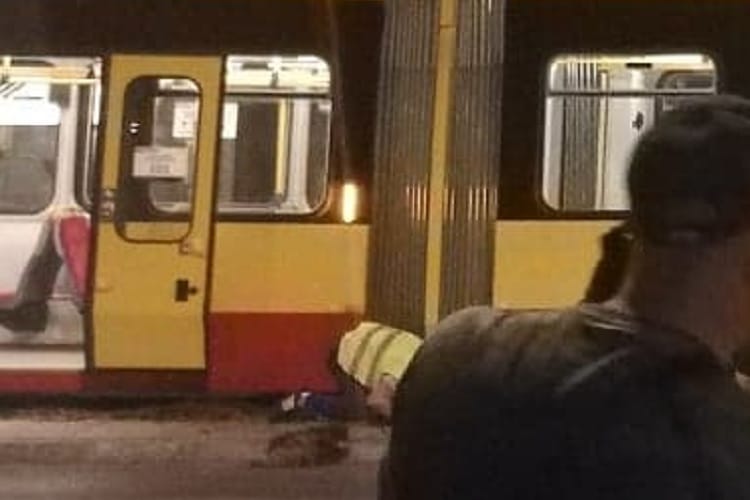 Osoba leżąca obok tramwaju po wypadku.