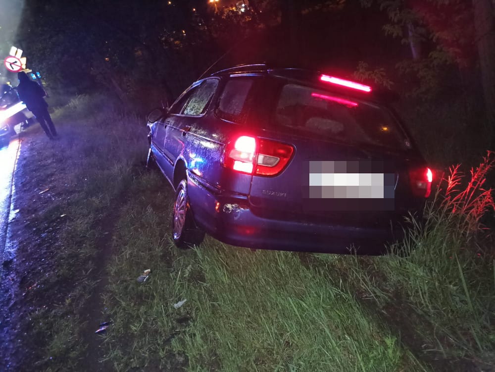 Ciemne kombi Suzuki w przydrożnym rowie nocą.