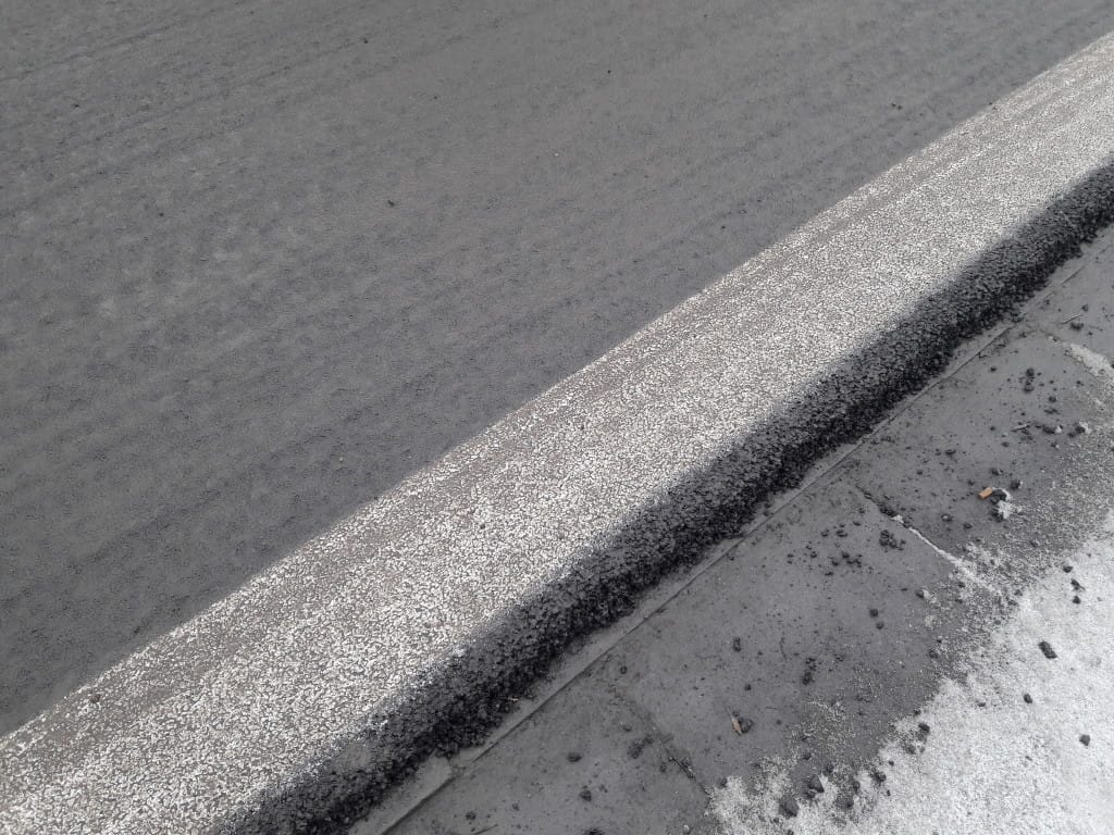 Świeża asfaltowa droga z nowo pomalowanym białym krawężnikiem